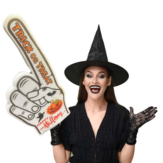 A person wearing a black witch costume and holding a white foam hand with 'Trick or Treat' printed on it, also with a pumpkin and bat design.